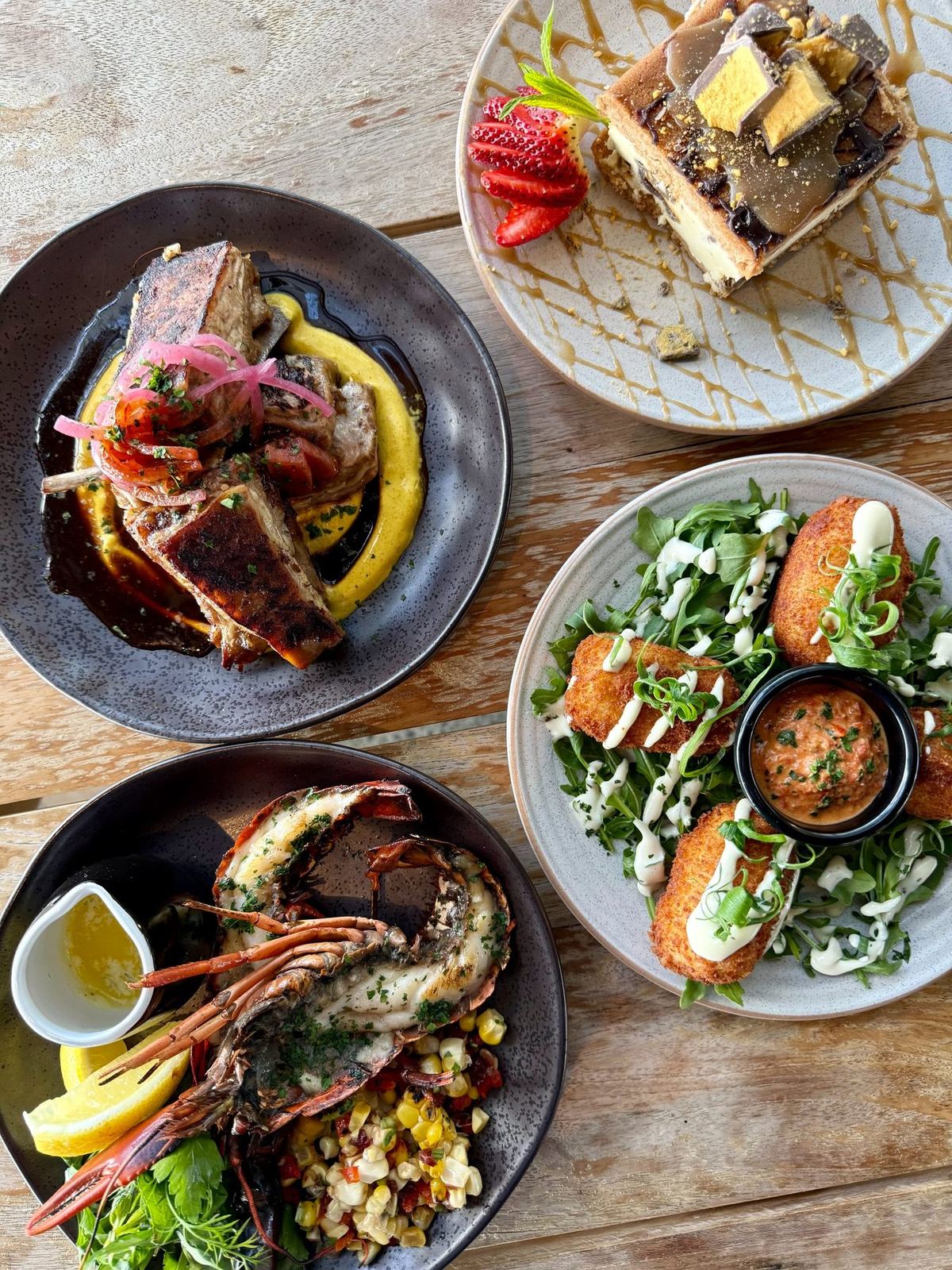 An overhead spread — grilled marron, pork ribs, croquettes and dessert